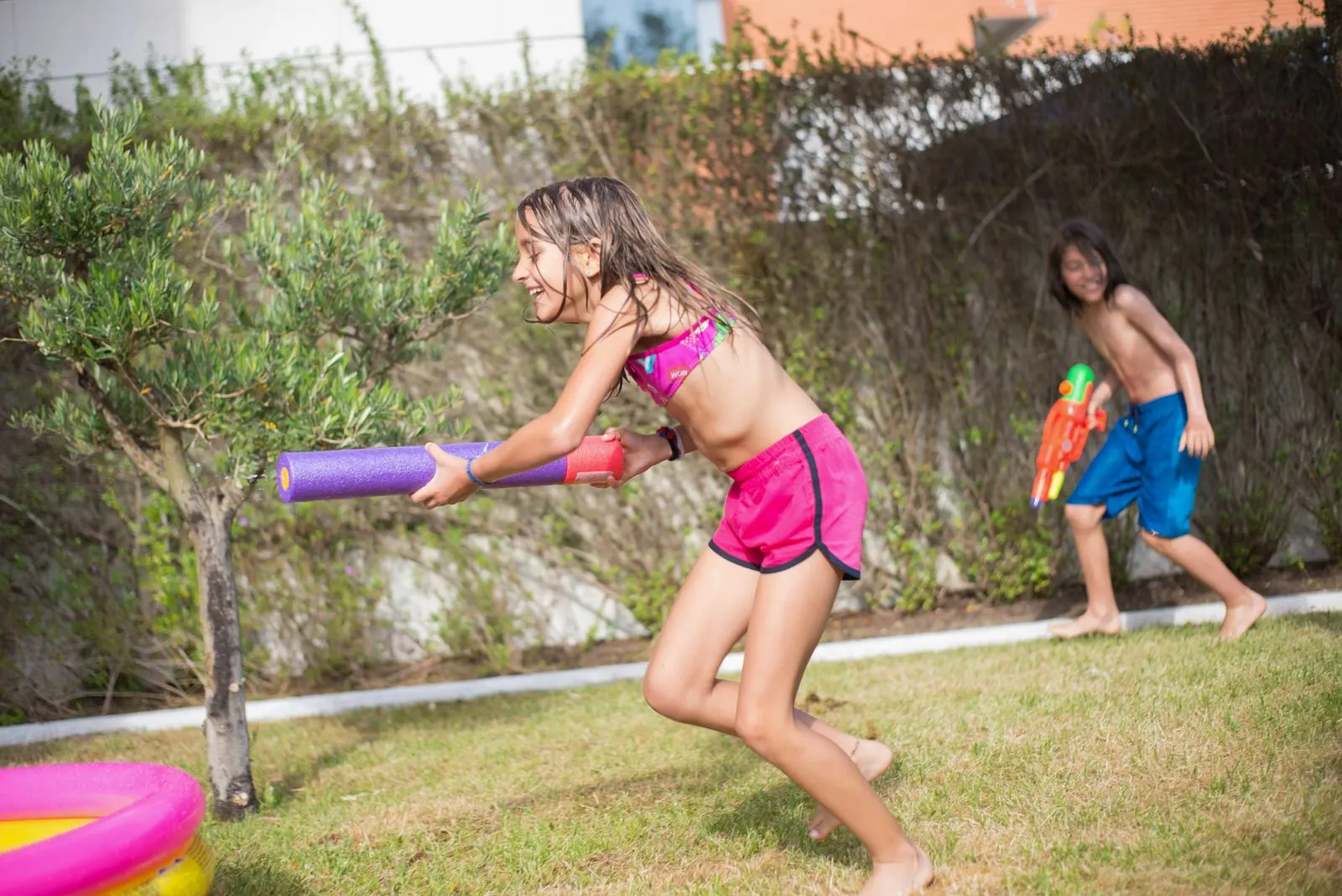 Enfants en pleine bataille d'eau avec des pistolets à eau dans un jardin ensoleillé